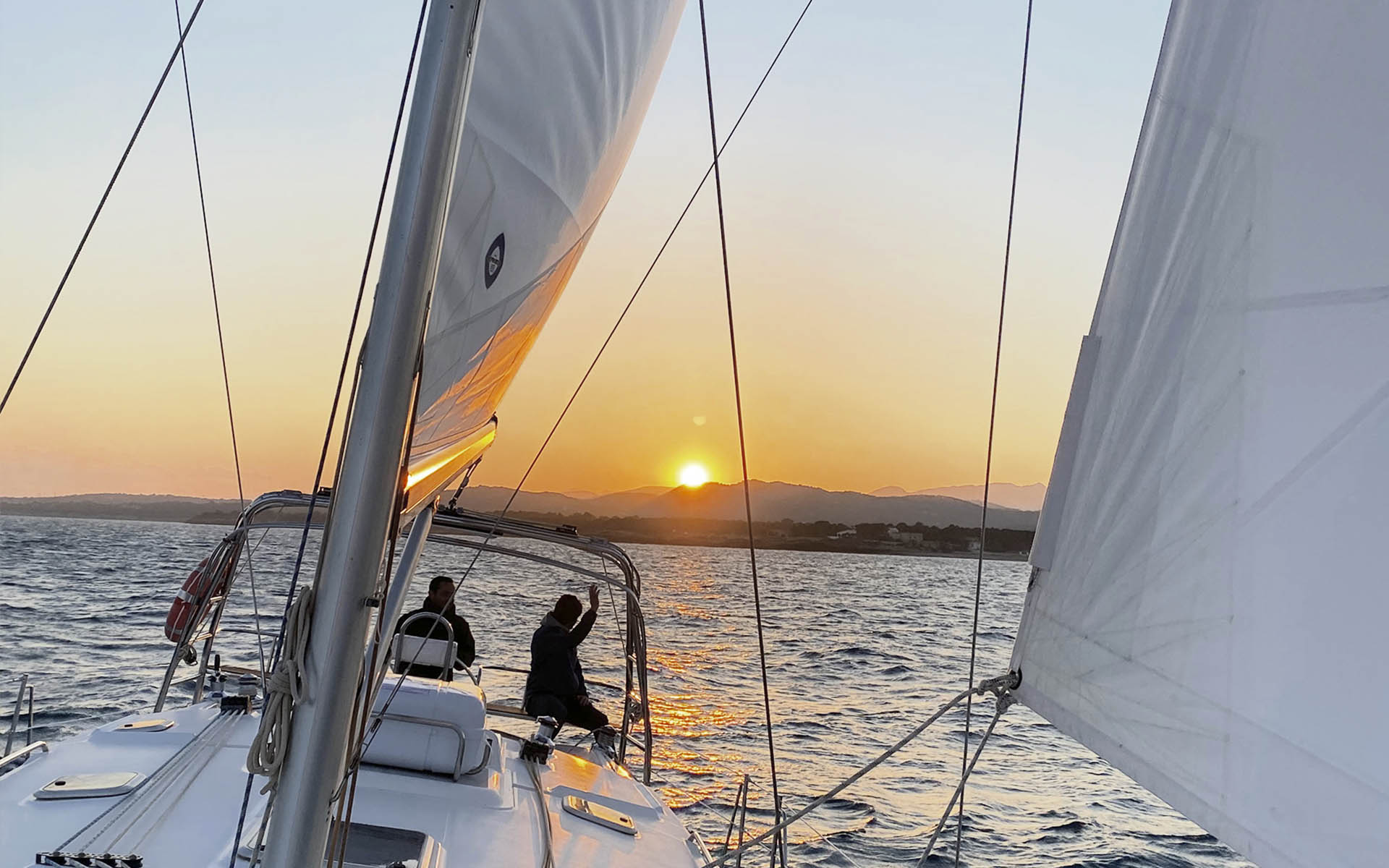 Velero navegando frente a la costa al atardecer
